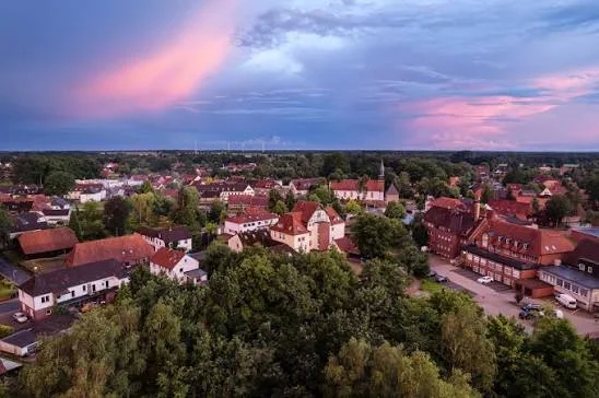 Luftaufnahme von Bergen mit roten Dächern und viel Grün in der Abenddämmerung